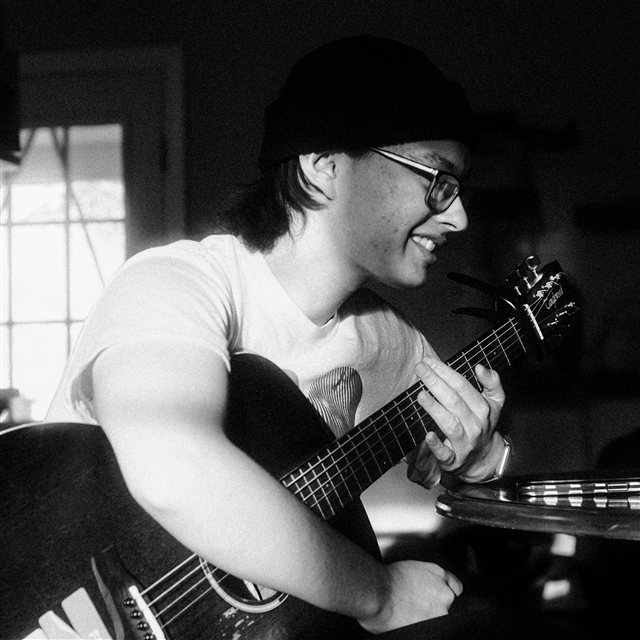 Avery Johnson playing an acoustic guitar